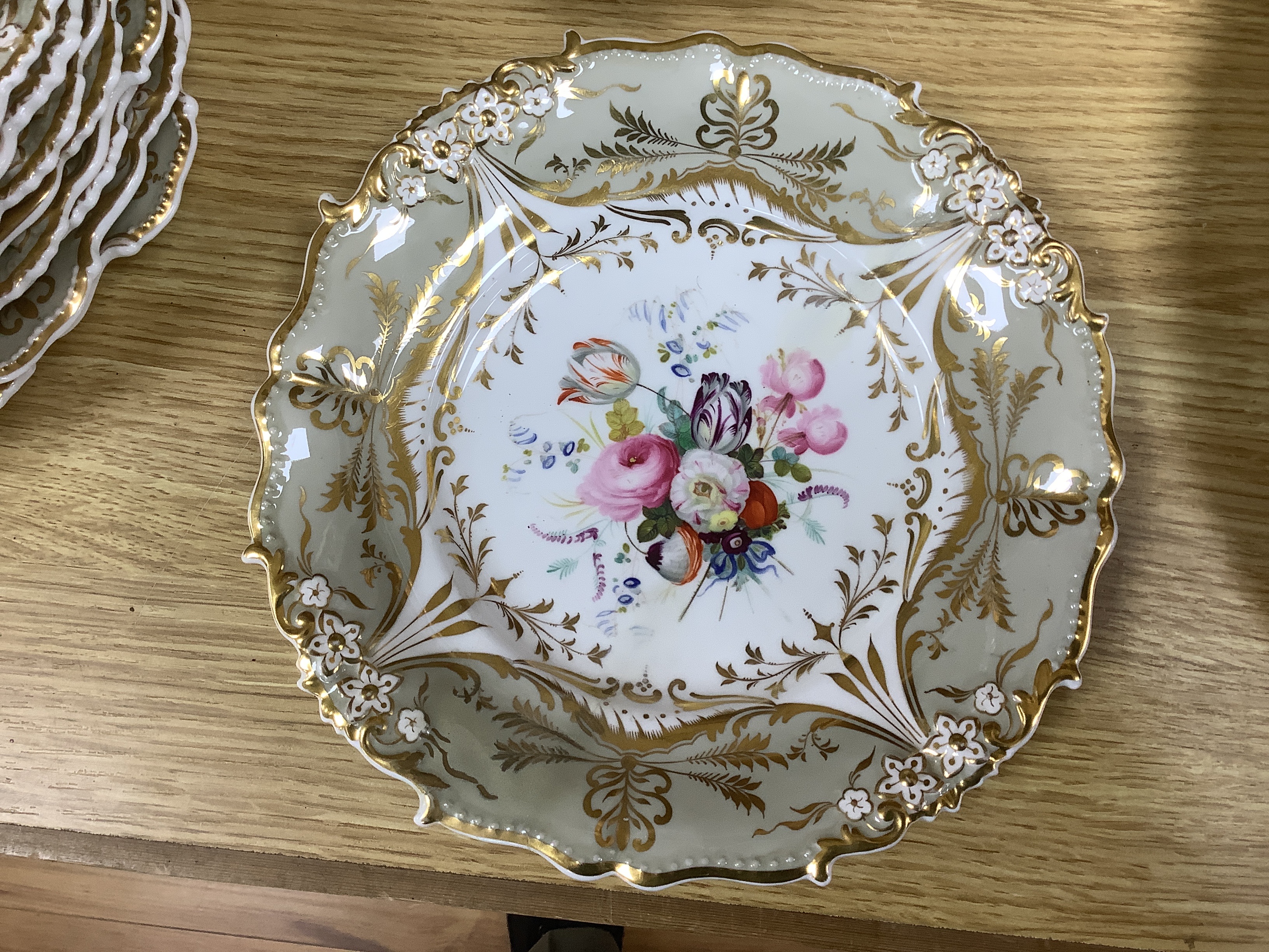 A Davenport porcelain part dessert service, each piece painted with a differing floral bouquet, within shaped grey and gilt borders